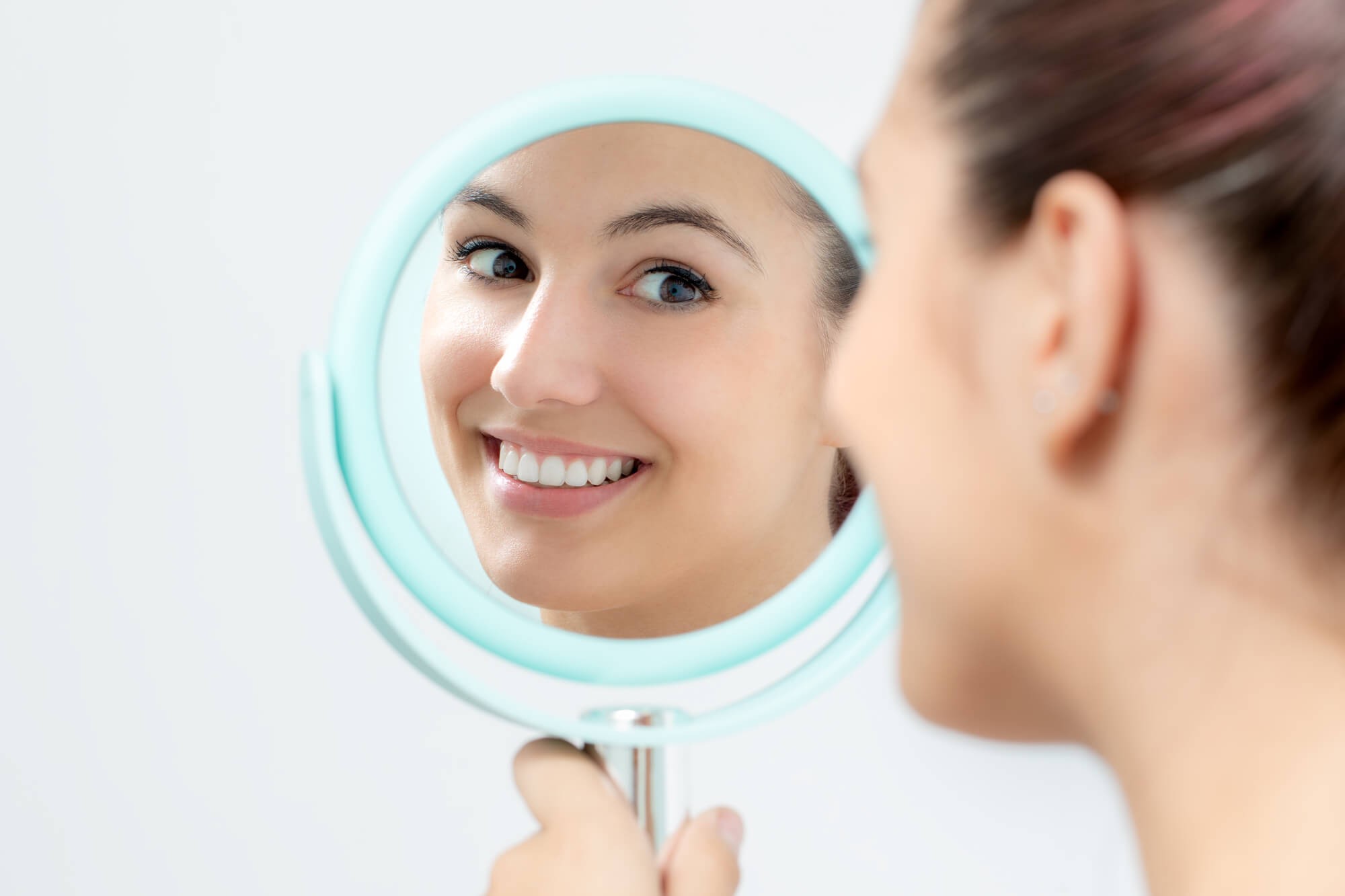 woman looking in the mirror after undergoing cosmetic dentistry in miami fl