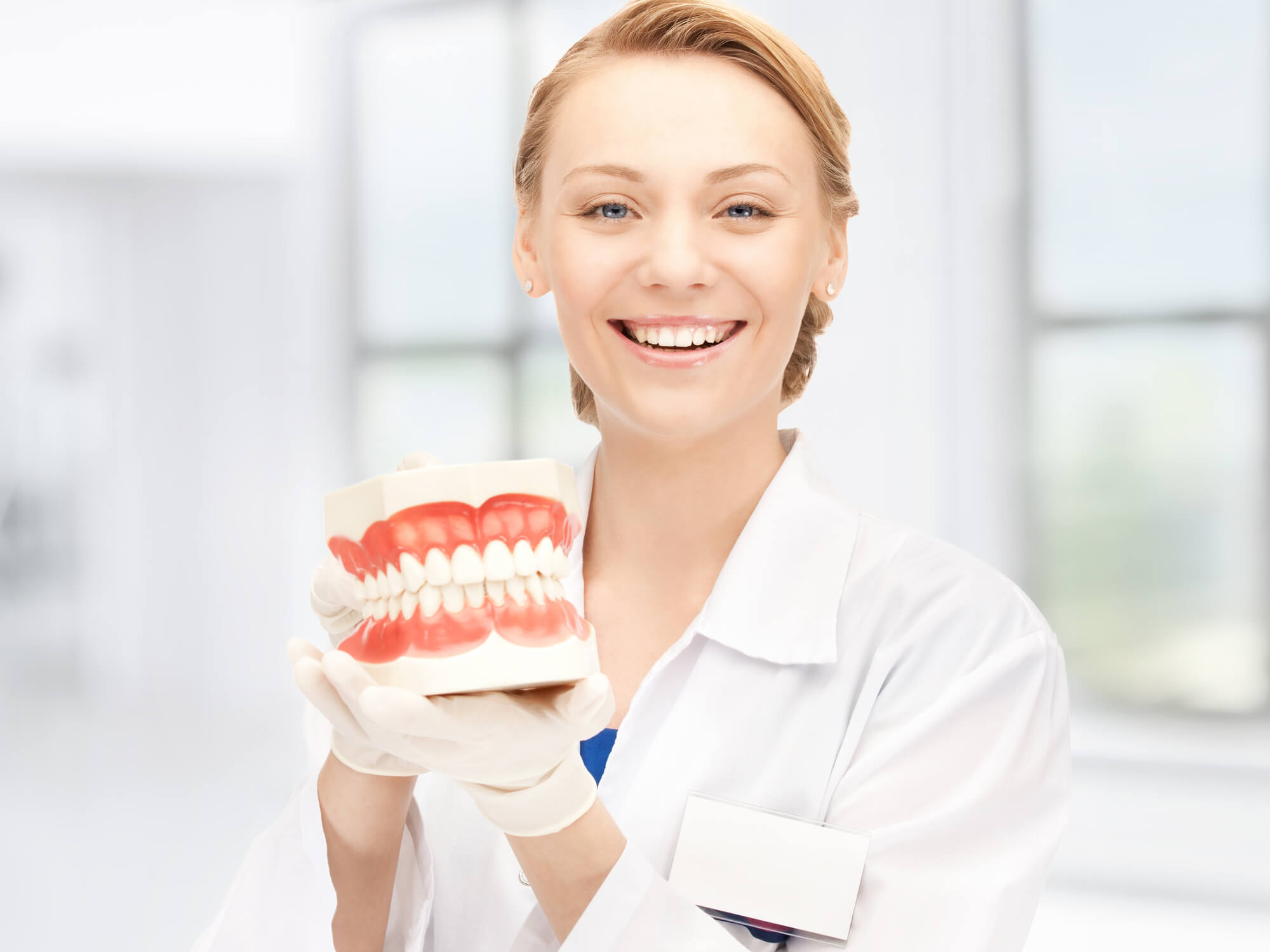 dentist expert in periodontics Miami smiles while holding teeth model
