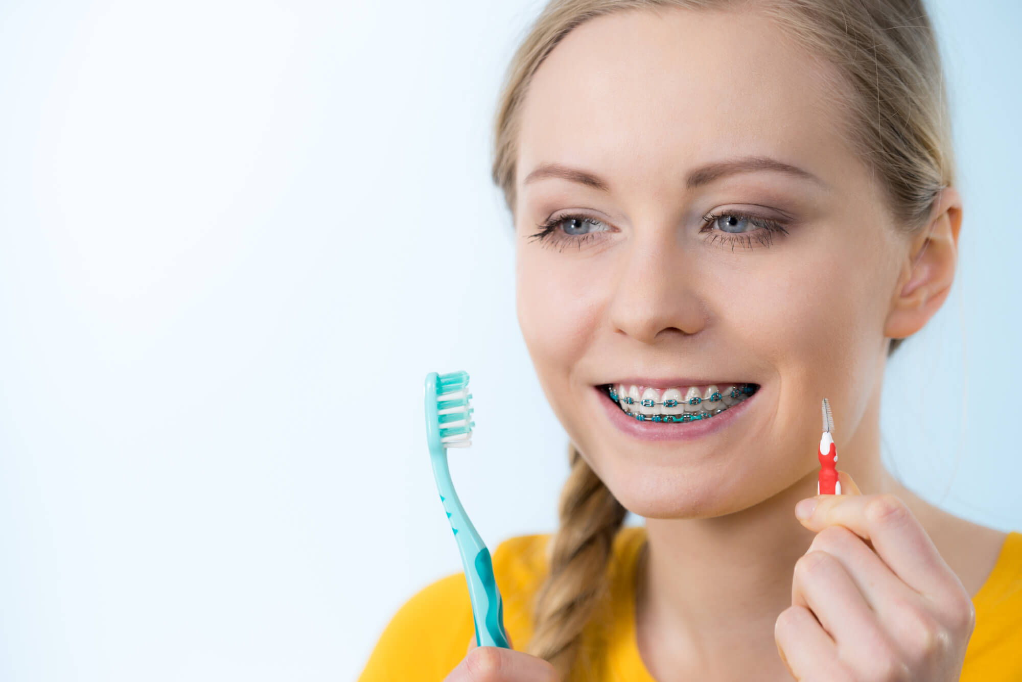 woman with braces about to brush her teeth as advised by miami orthodontic specialists